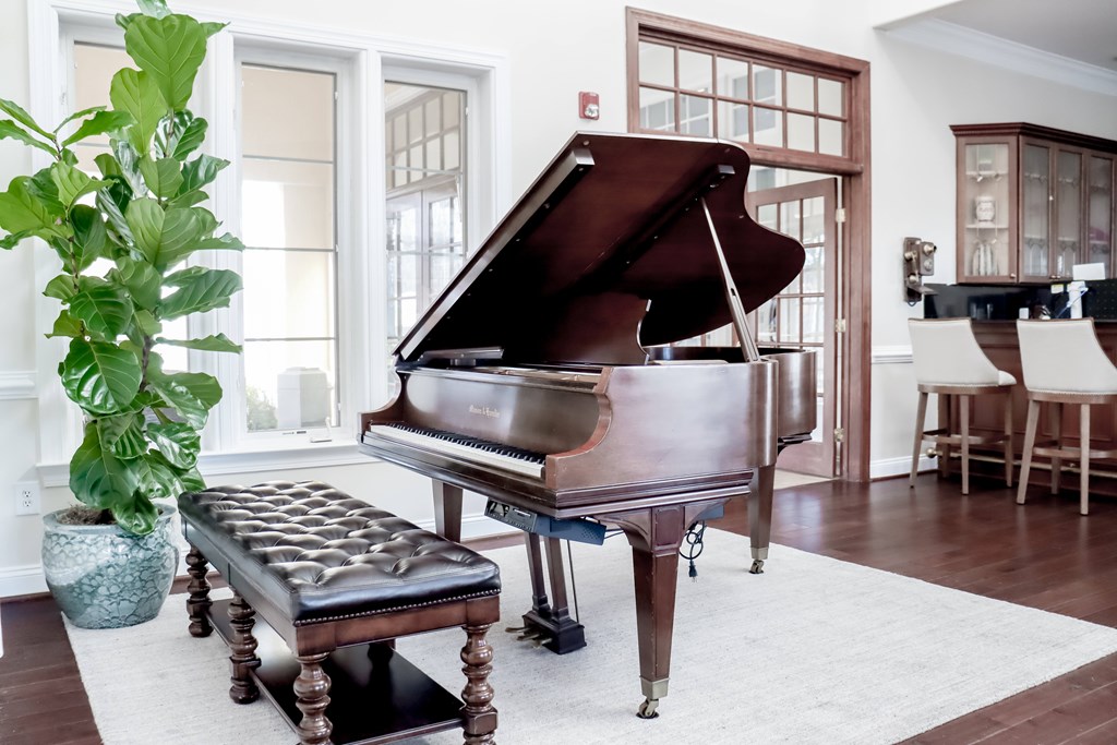 a piano in a living room with a potted plant at Broadlands Apartments in Ashburn